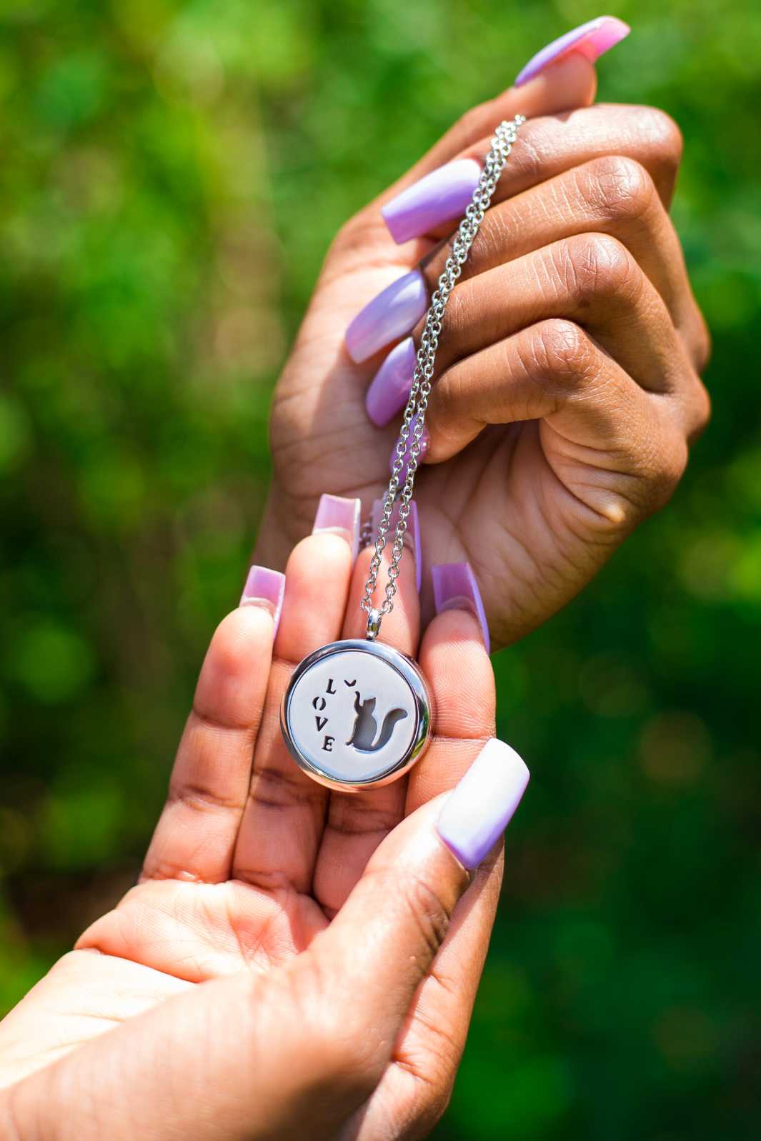 Young woman holding up the lovely Cat Memorial Locket from online keepsake jewelry shop they made me wear it. Now you can safely insert the ashes of your beloved into the beautiful keepsake.