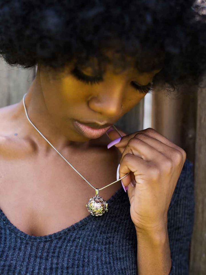 Black woman wearing beautiful keepsake jewelry, Hollow Ball Steampunk Memorial Urn Necklace in Rose Gold from online boutique they made me wear it. Free engraving available.