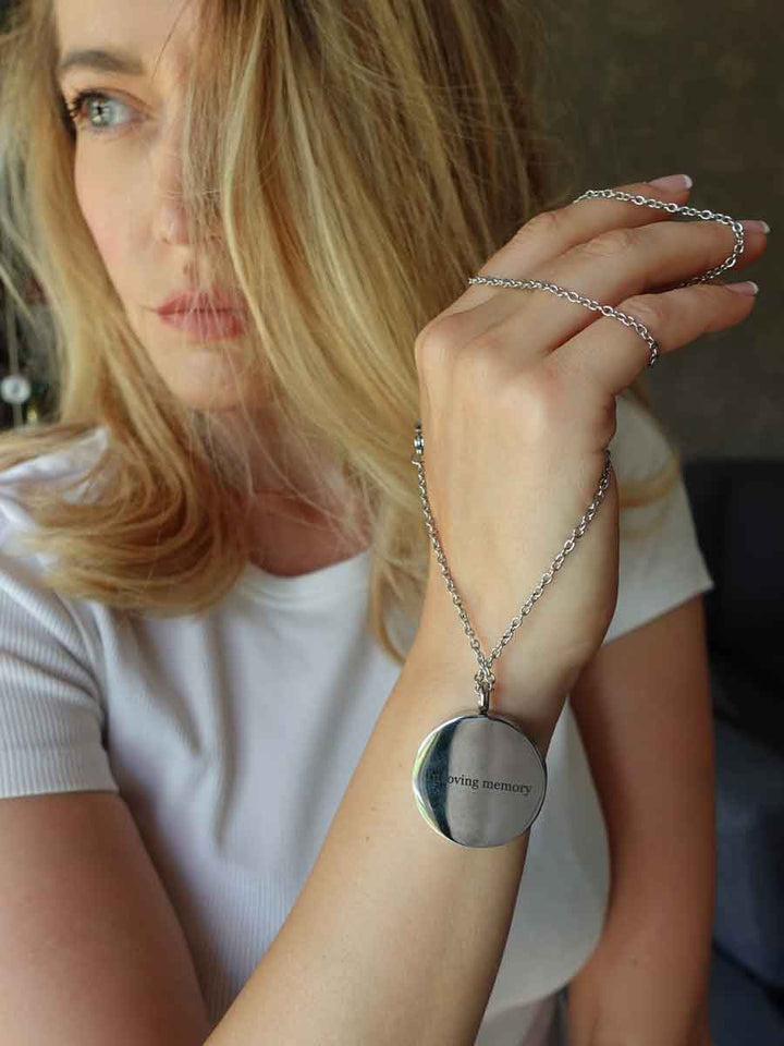 Woman holding up silver Tree of Life Memorial Locket. The perfect bereavement gift for family and friends who want a cremation locket to hold a small amount of pet ashes to remember their cat who crossed over the rainbow bridge. The locket can also be used as an aromatherapy essential oil diffuser as it comes with 12 free felt pads. Free engraving available from online boutique they made me wear it.