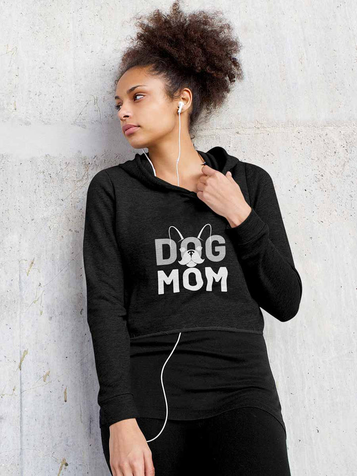 Young woman leaning against a wall, wearing the Black Dog Mom Cropped Hoodie from online outerwear and activewear clothing store for pet parents, they made me wear it.